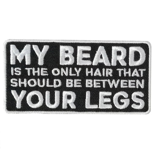 A black and white embroidered patch with the text 'MY BEARD IS THE ONLY HAIR THAT SHOULD BE BETWEEN YOUR LEGS'.