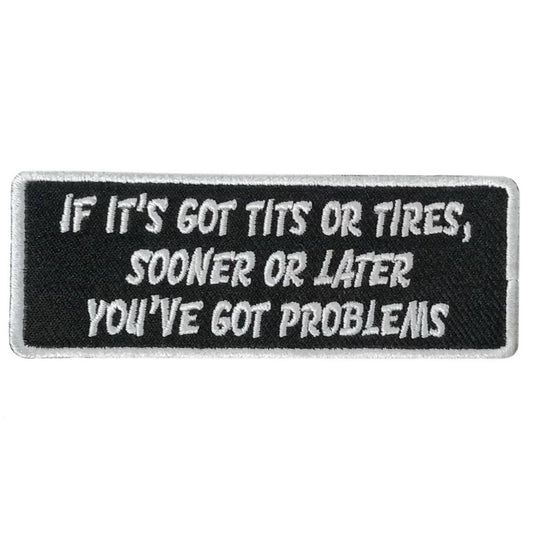 A rectangular black patch with white text that reads: 'IF IT'S GOT TITS OR TIRES, SOONER OR LATER YOU'VE GOT PROBLEMS'.