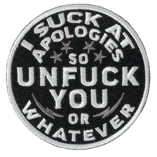 A circular black and white embroidered patch with the text 'I SUCK AT APOLOGIES SO UNFUCK YOU OR WHATEVER'.