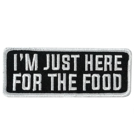 A rectangular black and white embroidered patch with the text 'I'M JUST HERE FOR THE FOOD' on it.