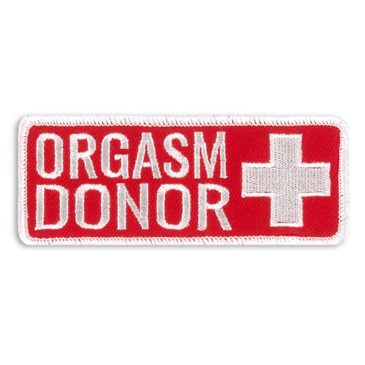 A red and white embroidered patch with the text 'ORGASM DONOR' and a medical cross design